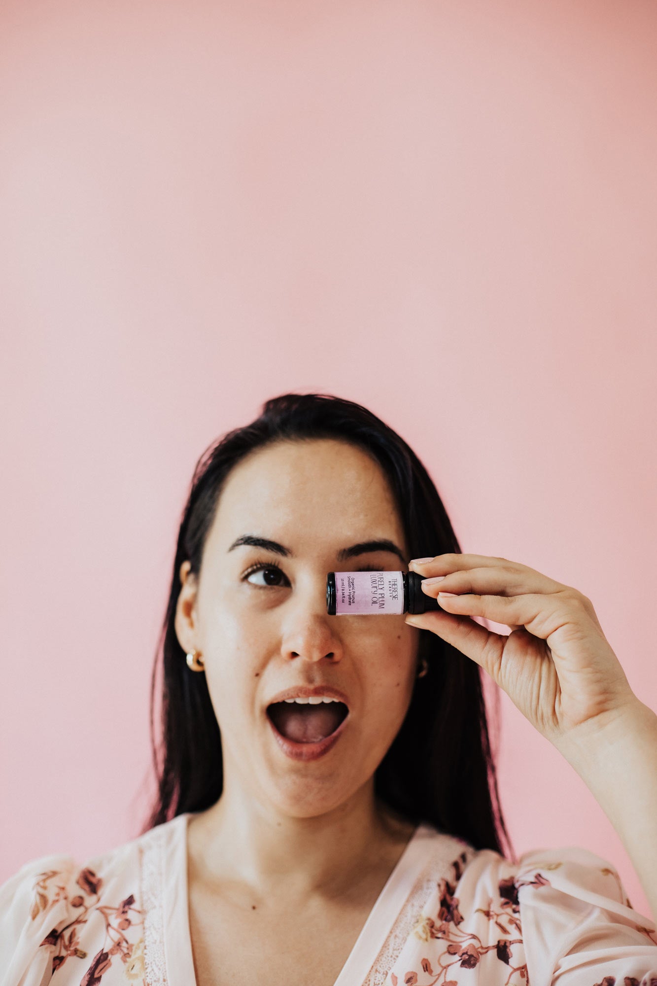 Woman holding a small product container against a pink background